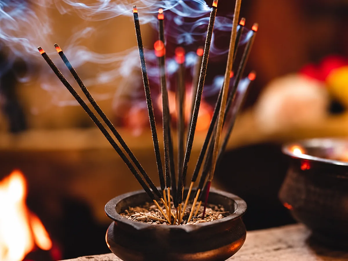Burning incense sticks in a traditional pot with fragrant smoke rising
